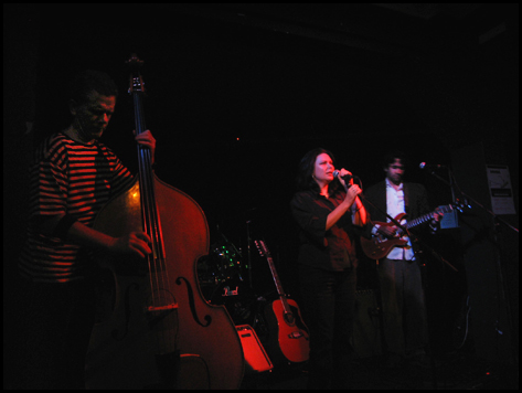 Letterbox performing on a dark stage, with double bass in the foreground